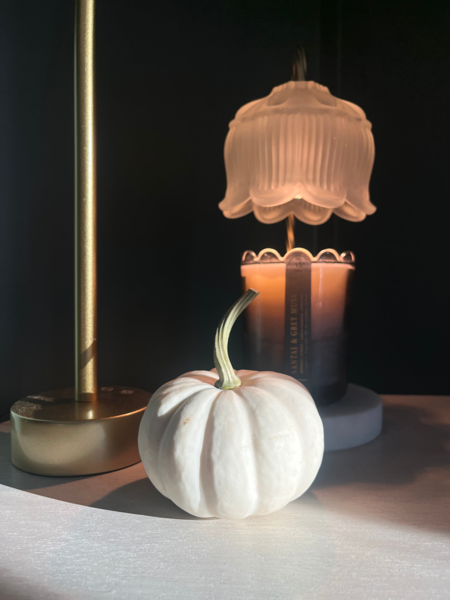 A small pumpkin beside a candle warmer lamp in the evening